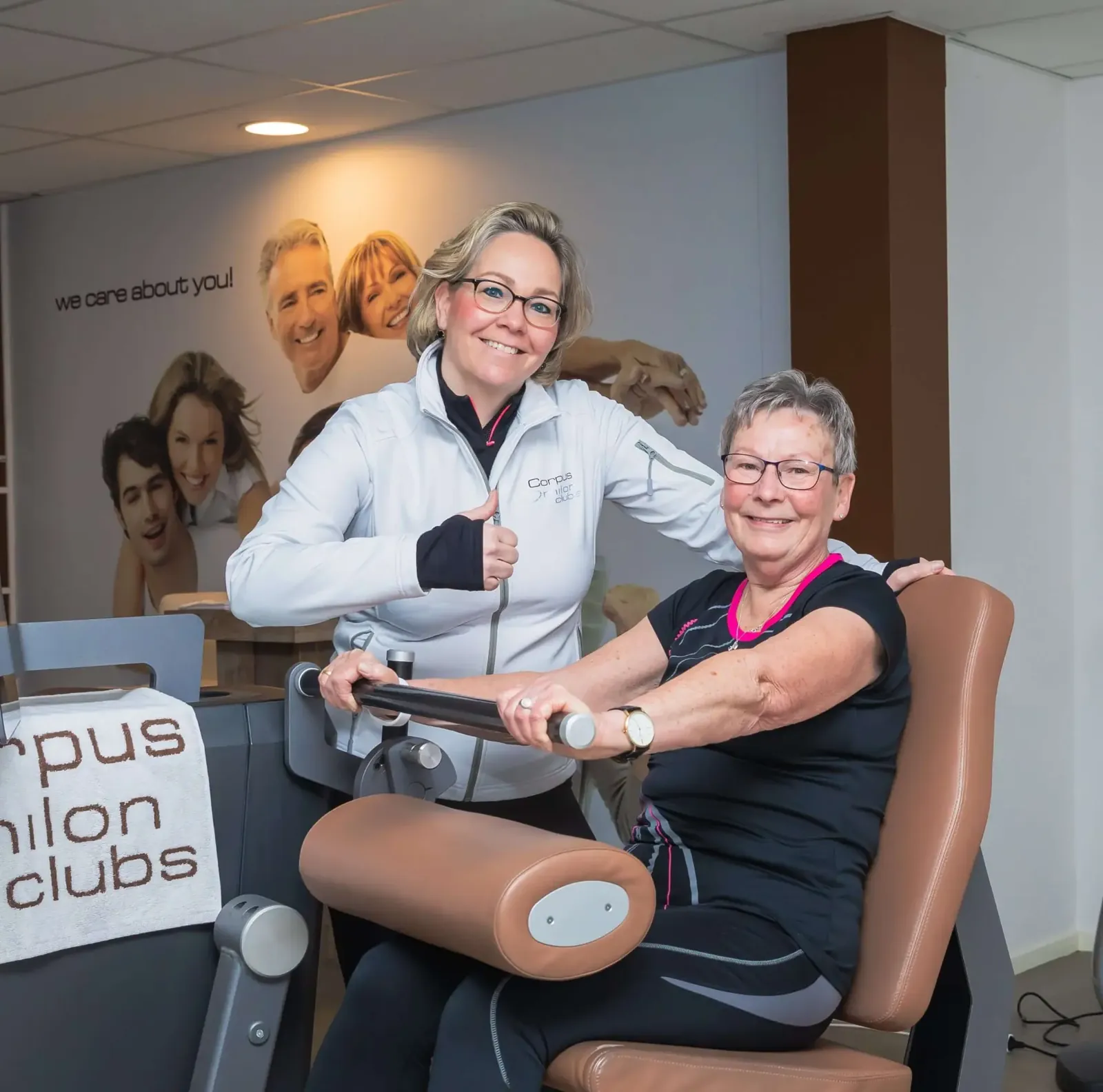 Coach begeleidt een ouder lid op een Milon-beentoestel